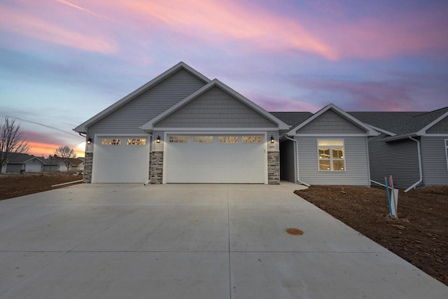 craftsman inspired home with a garage, stone siding, and concrete driveway