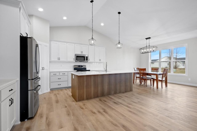 kitchen featuring light wood finished floors, stainless steel appliances, light countertops, white cabinetry, and tasteful backsplash