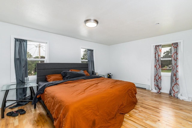 bedroom featuring a baseboard heating unit and light wood-style flooring