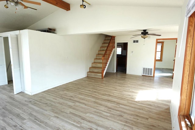 empty room featuring visible vents, vaulted ceiling with beams, ceiling fan, stairs, and light wood-style floors