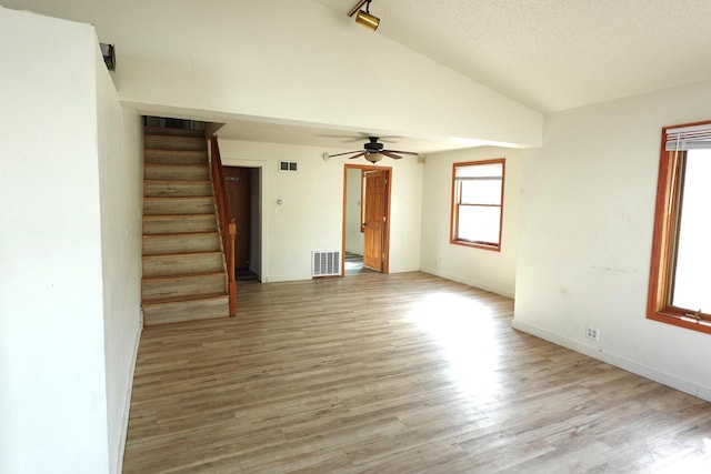 unfurnished living room with visible vents, lofted ceiling, wood finished floors, and stairs