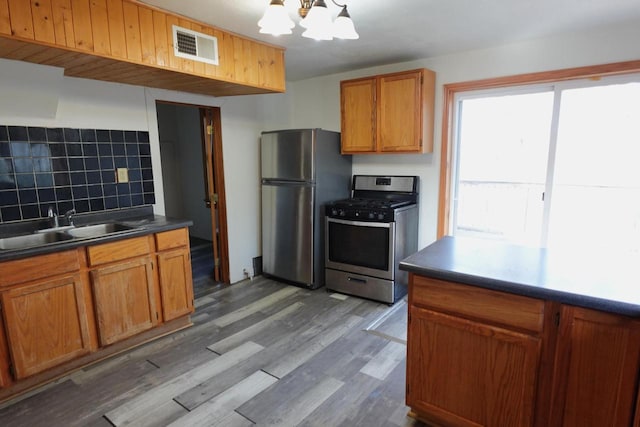 kitchen featuring visible vents, dark wood-type flooring, a sink, backsplash, and stainless steel appliances