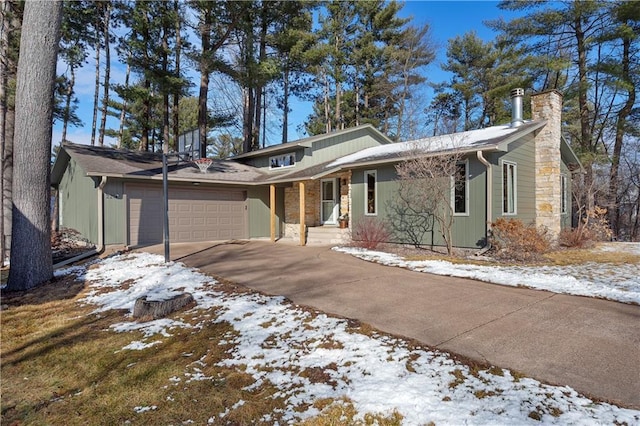 view of front of house featuring concrete driveway, an attached garage, and a chimney