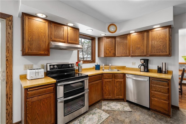 kitchen featuring a sink, light countertops, under cabinet range hood, and stainless steel appliances