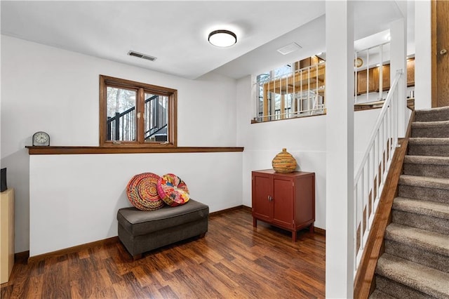 living area with visible vents, baseboards, wood finished floors, and stairs