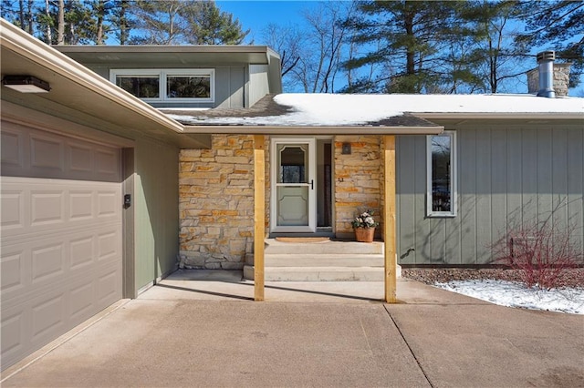 doorway to property featuring stone siding and an attached garage