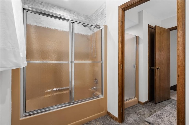 full bath featuring baseboards and shower / bath combination with glass door