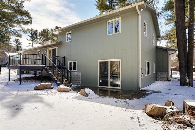 snow covered property with stairway and a wooden deck