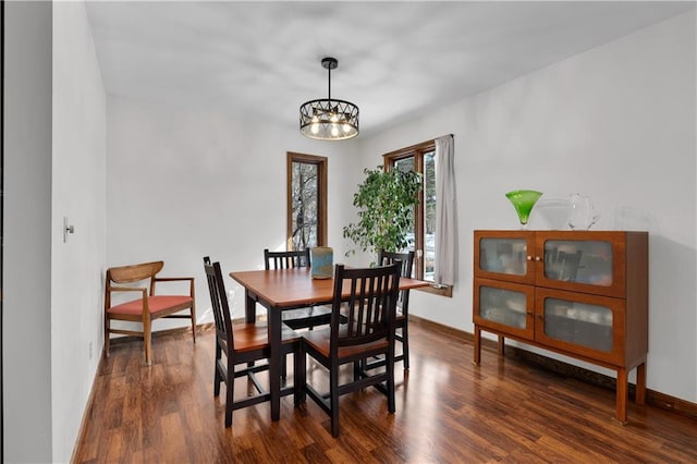 dining area with an inviting chandelier, baseboards, and dark wood-style flooring