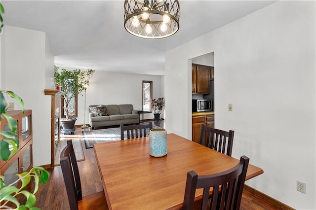 dining room with a notable chandelier, baseboards, and dark wood-style flooring