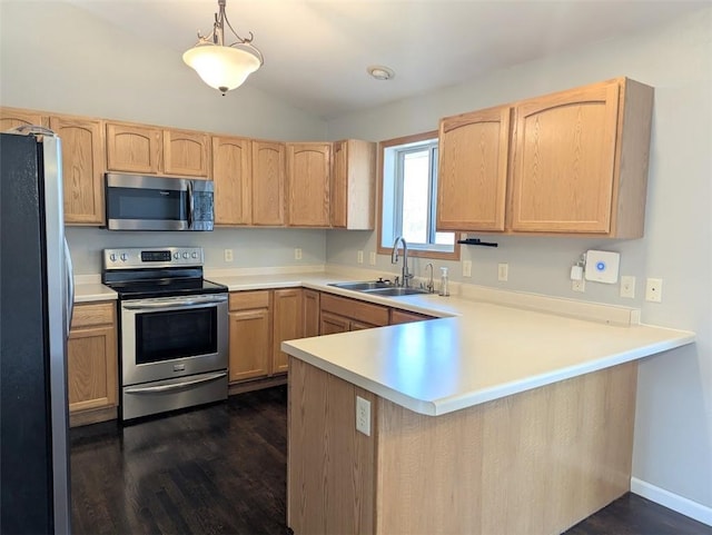 kitchen with a peninsula, a sink, light brown cabinetry, light countertops, and stainless steel appliances