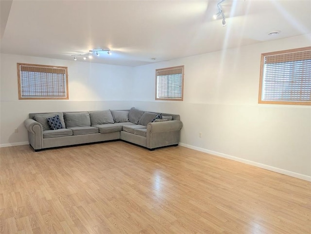 unfurnished living room featuring rail lighting, light wood-style floors, and baseboards