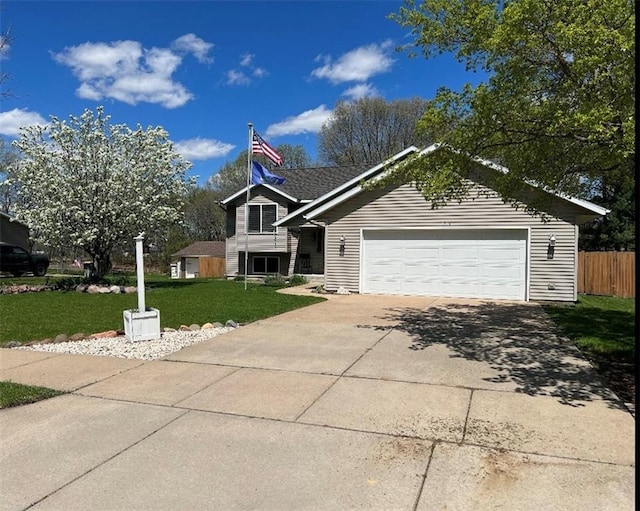 view of front of home with driveway, an attached garage, a front yard, and fence