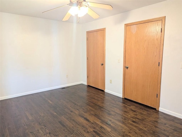 unfurnished bedroom with visible vents, baseboards, dark wood-type flooring, and ceiling fan