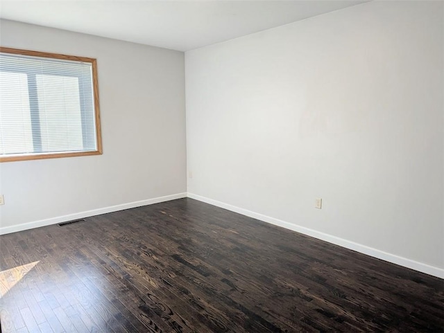 unfurnished room featuring visible vents, baseboards, and dark wood-style flooring