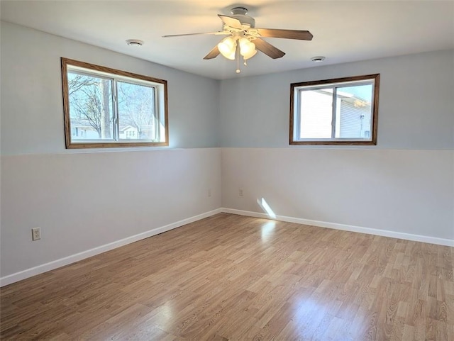 spare room with plenty of natural light, light wood-style flooring, baseboards, and ceiling fan