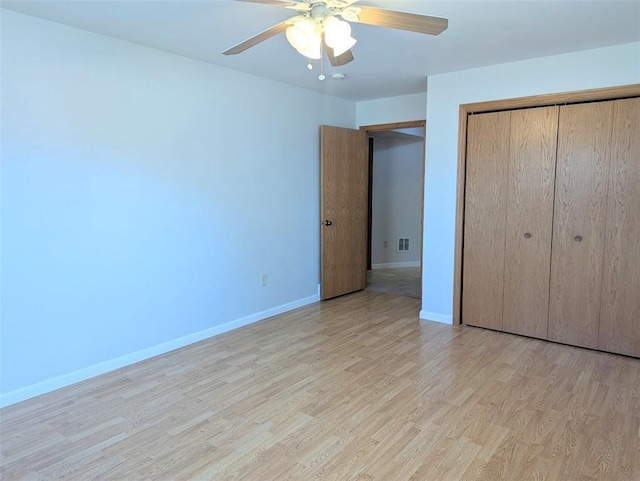 unfurnished bedroom with visible vents, light wood-style floors, baseboards, and a closet