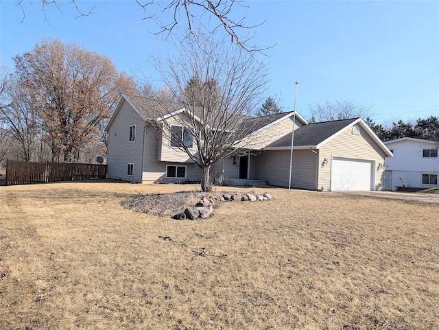 tri-level home featuring a garage, a front lawn, and fence