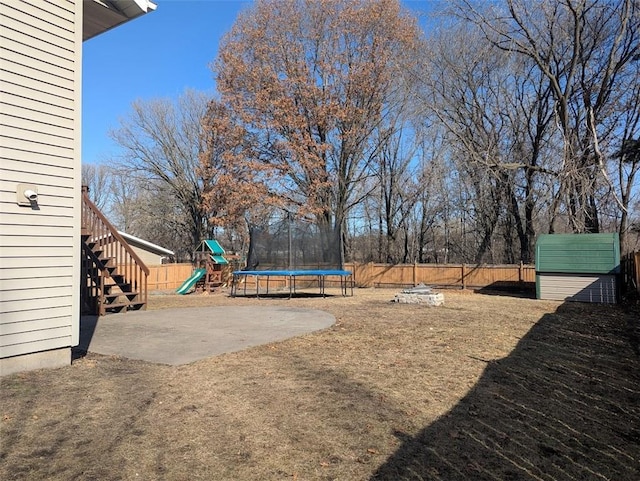 view of yard with a patio, a trampoline, a fenced backyard, and a playground