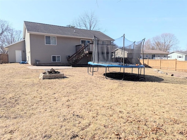 back of property with stairway, a trampoline, and fence