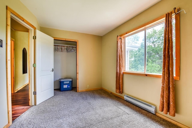 unfurnished bedroom featuring a baseboard heating unit, a closet, and carpet floors