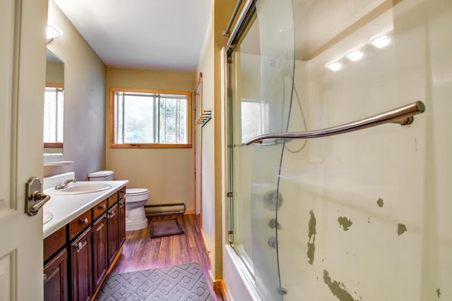 bathroom with vanity, wood finished floors, toilet, combined bath / shower with glass door, and baseboard heating