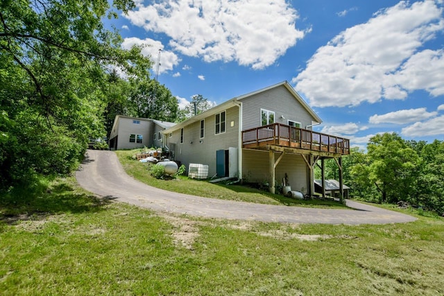 view of side of property featuring central AC unit, a lawn, driveway, and a wooden deck