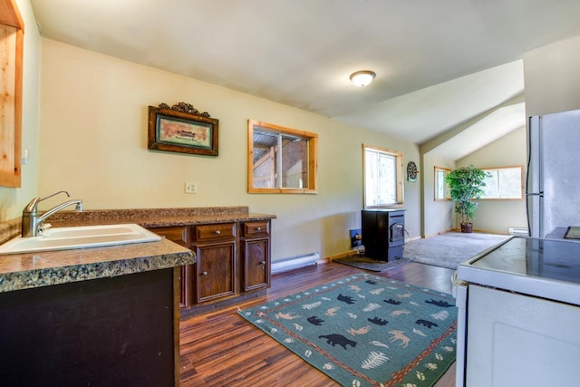 kitchen with white appliances, a wood stove, a sink, dark wood-type flooring, and a baseboard heating unit