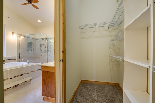 bathroom with a stall shower, a ceiling fan, baseboards, a bath, and vanity