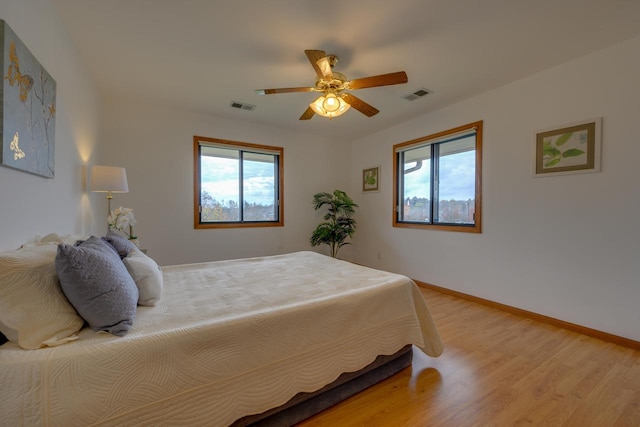 bedroom featuring visible vents, multiple windows, and light wood-style flooring