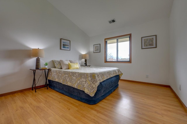 bedroom featuring visible vents, light wood-style flooring, baseboards, and lofted ceiling