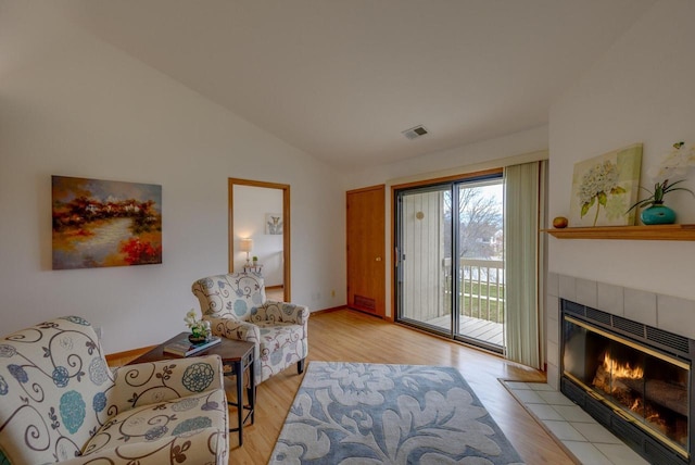 sitting room featuring visible vents, baseboards, light wood-type flooring, lofted ceiling, and a fireplace