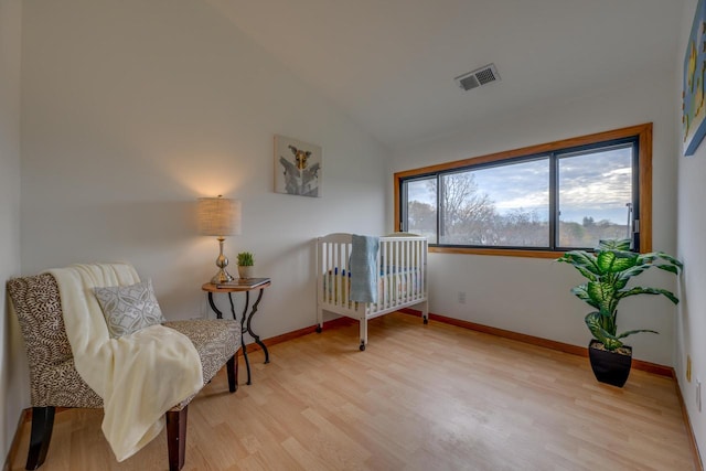 living area with visible vents, baseboards, light wood-style floors, and lofted ceiling