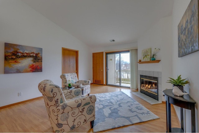 living room with light wood-type flooring, visible vents, high vaulted ceiling, baseboards, and a tile fireplace