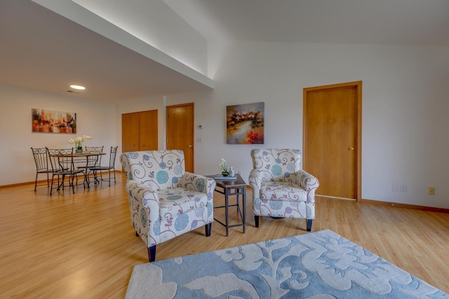 living area with lofted ceiling, baseboards, and wood finished floors