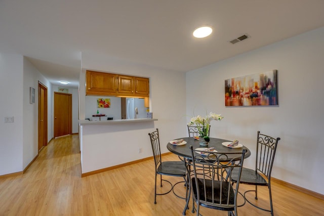 dining area featuring light wood-style flooring, baseboards, and visible vents