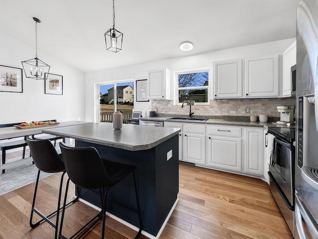 kitchen featuring a sink, light wood-type flooring, dark countertops, and a breakfast bar