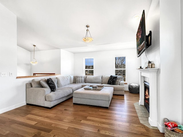 living area with a fireplace with flush hearth, baseboards, and wood finished floors