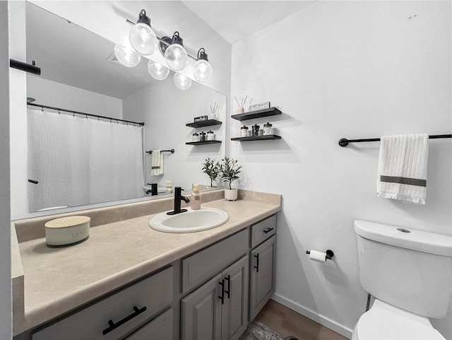 full bathroom featuring baseboards, toilet, and vanity