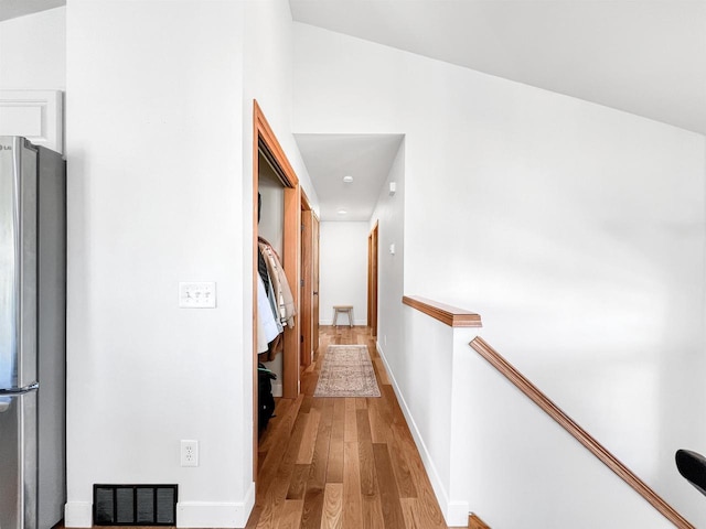 hallway featuring an upstairs landing, wood finished floors, visible vents, and baseboards