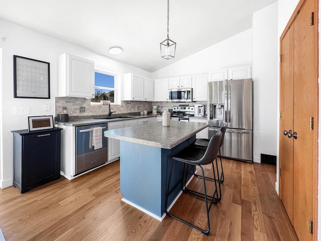 kitchen featuring a kitchen island, light wood-style flooring, a sink, stainless steel appliances, and backsplash