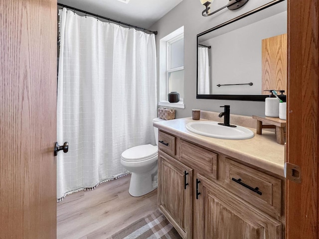 bathroom with vanity, curtained shower, toilet, and wood finished floors