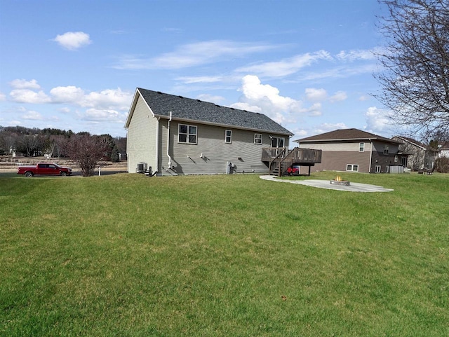 back of house with an outdoor fire pit, a lawn, and a wooden deck