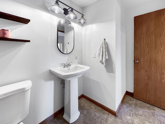 half bathroom with tile patterned flooring, toilet, and baseboards