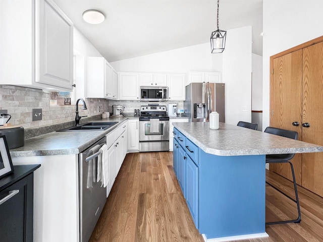 kitchen with appliances with stainless steel finishes, white cabinetry, a kitchen breakfast bar, and a sink