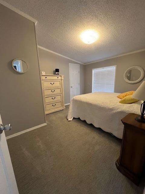 carpeted bedroom with a textured ceiling, lofted ceiling, and ornamental molding