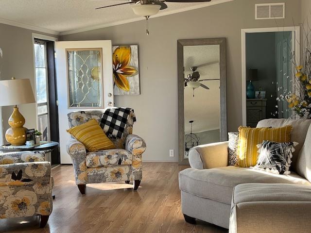 sitting room featuring visible vents, crown molding, ceiling fan, lofted ceiling, and wood finished floors