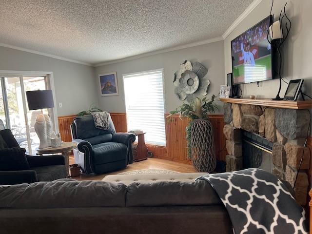 living area with a fireplace, wood finished floors, a healthy amount of sunlight, and ornamental molding