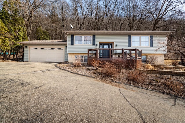 raised ranch with aphalt driveway, an attached garage, and brick siding