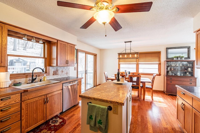 kitchen with a wealth of natural light, dishwasher, light wood-style floors, and a sink